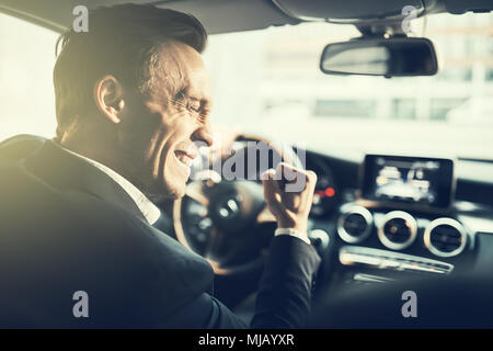 Ecstatic young businessman celebrating success with a fist pump while driving to work in is car during his morning commute Stock Photo