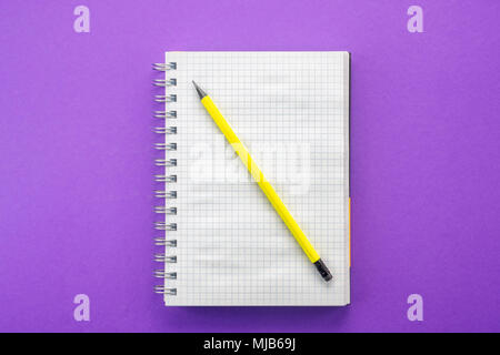 Notepad for notes and graphite pencil on purple paper background Concept Back to School copy space close up top view Stock Photo