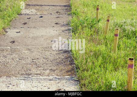 Sidewalk with concrete slabs and rusty low stakes fence Stock Photo