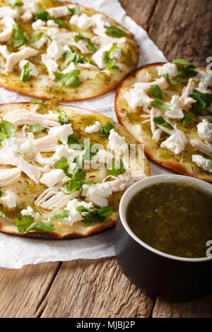 Mexican fast food Chalupas with fresh cheese and chicken meat and green sauce close-up on the table. vertical Stock Photo