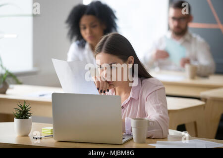 Serious employee attentively reading document focused on thinkin Stock Photo