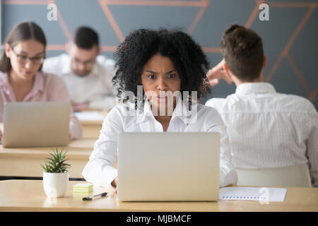Shocked african-american woman looking at laptop stressed with o Stock Photo
