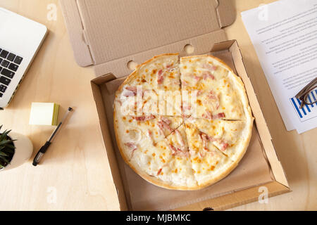 Italian pizza in cardboard box on work desk, top view Stock Photo