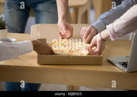 Multiracial people eating pizza during office lunch, close up vi Stock Photo