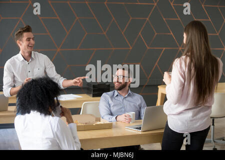 Cheerful millennial team people joking and laughing eating pizza Stock Photo