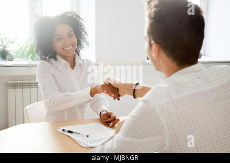 Smiling millennial african woman handshaking partner in office m Stock Photo