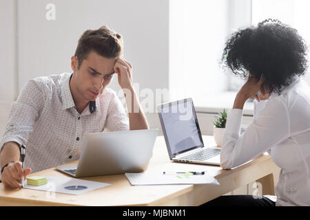 Frustrated stressed african and caucasian colleagues shocked abo Stock Photo