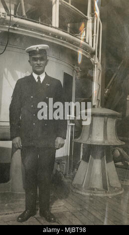 Antique c1922 photograph, view aboard the cable ship USCG Pequot. An officer in a US Coast Guard uniform, near the large electric capstan on the deck. SOURCE: ORIGINAL PHOTOGRAPHIC PRINT. Stock Photo