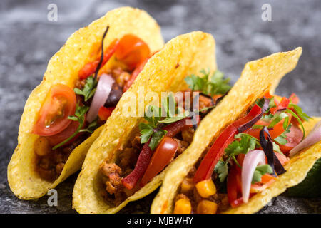 Three Colorful Mexican Tacos in Shells on Stone Background Stock Photo