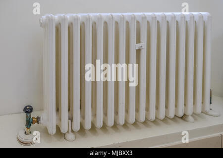 Metal radiator, old and painted in white but still functional. Stock Photo