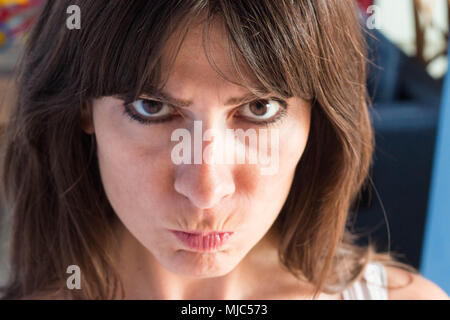 close up portrait of caucasian young woman with long hair and bangs. funny, blaming, angry Expression. Stock Photo