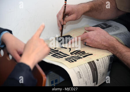 Defense Language Institute Foreign Language Center (DLIFLC) provides instruction in multiple foreign languages for U.S. Army personnel. The archival image documents students engaging in Chinese calligraphy as an extracurricular activity, supporting cultural exposure and practice of traditional script. The historical photographic print records classroom learning and handwriting exercises. Stock Photo