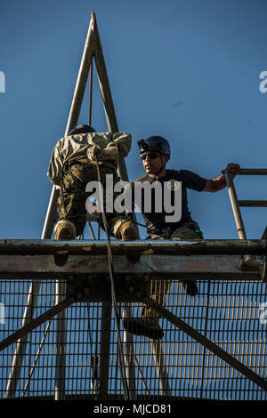 U.S. Marine Corps Sgt. Jarrod Johnson, a field training instructor with Weapons and Field Training Battalion prepares a recruit of Mike Company, 3rd Recruit Training Battalion, to rappel  May 1, 2018, on Parris Island, S.C. Instructors, like Johnson, 24, from Jacksonville, Fla., are responsible for the safety of the recruits as well as teaching them how to rappel from the 47-foot-tall tower. Mike Company is scheduled to graduate July 6, 2018. (Photo by Lance Cpl. Carlin Warren) Stock Photo