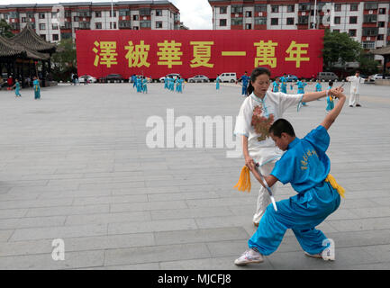 Young Chinese people training, child working out, boy exercising with sword for traditional martial arts in Tianshui city square, China, Asia Stock Photo