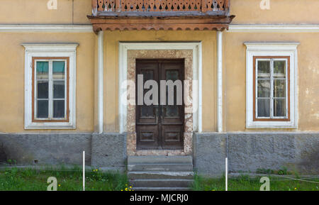 Facade of an uninhabited traditional house with a wooden balcony over the entrance door Stock Photo
