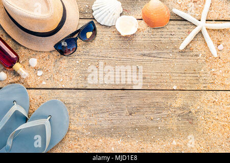 Summer accessories as hat, shells and sun glasses on wooden and sandy background Stock Photo