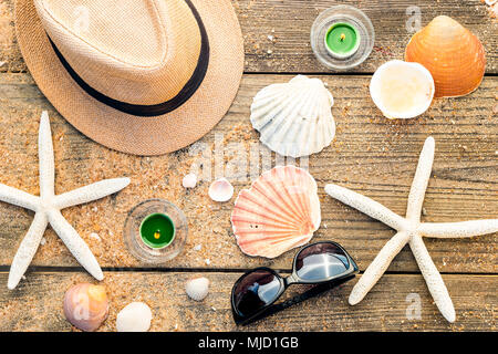 Summer concept and background made of accessories as hat, shells and sun glasses on wooden and sandy background Stock Photo