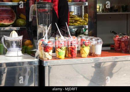 Fresh sliced fruits in plastic cups smoothie seller stall Stock Photo