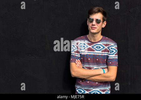 young man with sunglasses in front of black wall, arms crossed, half portrait, Stock Photo