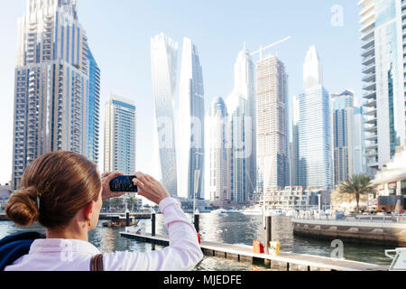 Dubai skyscrapers with Dubai Marina, female tourist taking a picture Stock Photo
