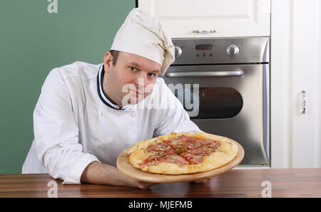 Chef the pizza master holding his product and showing it gentle and proudly to you Stock Photo