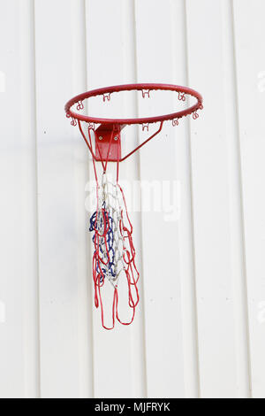 A broken basketball net mounted on light grey painted wooden wall. Stock Photo