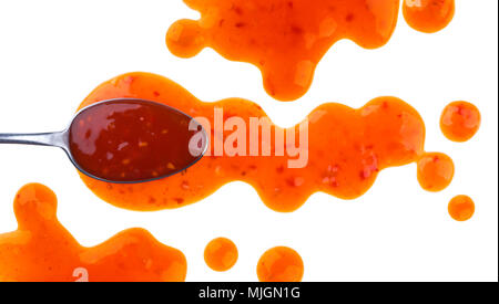 Sweet and sour sauce. Splashes and spilled orange sauce with spoon isolated on white background with clipping path. Top view Stock Photo