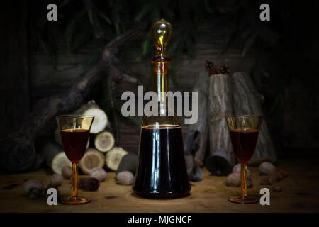 Red Wine Vintage Bottle and Glasses Resting On Wooden Table Against Christmas Background With Wood logs and Pine Branches Stock Photo