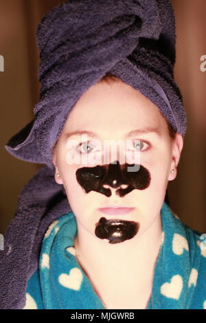 Women with a charcoal mask on as part of her beauty regime. This is a caucasian women who is aged 20 to 25 years old and is of British descent. Stock Photo