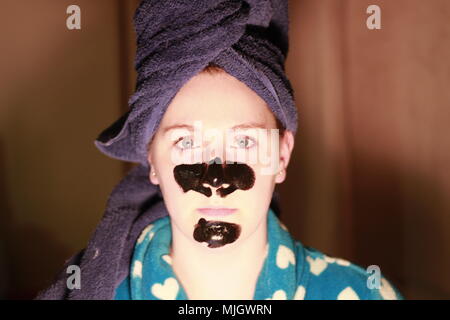 Women with a charcoal mask on as part of her beauty regime. This is a caucasian women who is aged 20 to 25 years old and is of British descent. Stock Photo