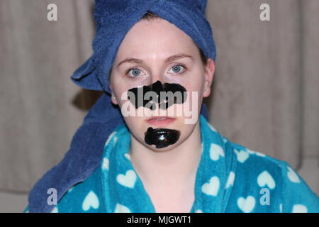 Women with a charcoal mask on as part of her beauty regime. This is a caucasian women who is aged 20 to 25 years old and is of British descent. Stock Photo