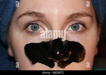 Women with a charcoal mask on as part of her beauty regime. This is a caucasian women who is aged 20 to 25 years old and is of British descent. Stock Photo