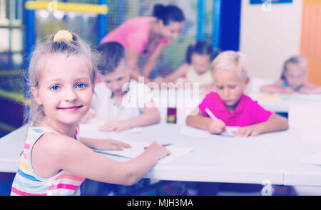 Portrait of cheerful smiling diligent pupil girl studying in school ...