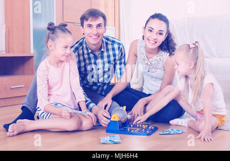 Family of four playing at lotto in domestic interior Stock Photo
