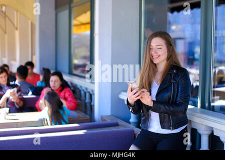 Charming woman chatting by smartphone at street cafe. Stock Photo