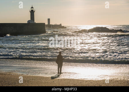 Man fishing from the beach in Foz do Douro district of Porto city, second largest city in Portugal. View with Felgueiras Lighthouse Stock Photo