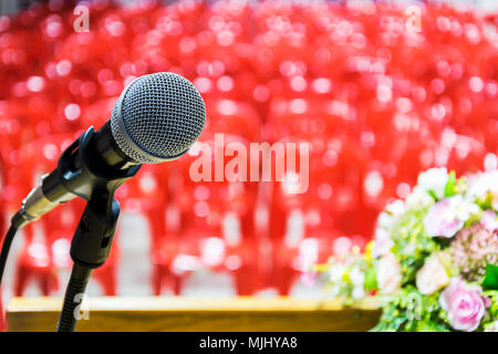 The microphone is located on the podium, with many red chairs arranged in the conference room, colorful flowers. Stock Photo