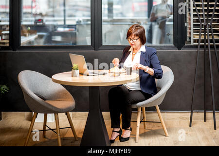 Senior business woman eating in the cafe Stock Photo