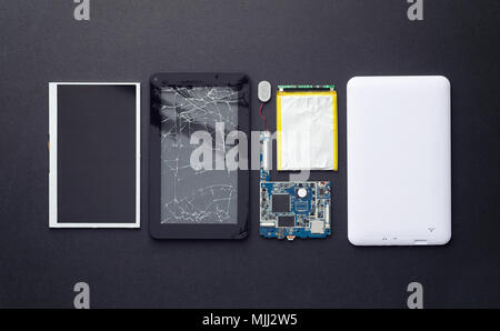 Components of a broken tablet organized over black background, top view Stock Photo