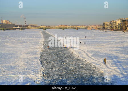 ST.PETERSBURG, RUSSIA - MARCH 07, 2018:  People walk along the frozen fairway, punched by an icebreaker on the Neva river against the Trinity bridge o Stock Photo