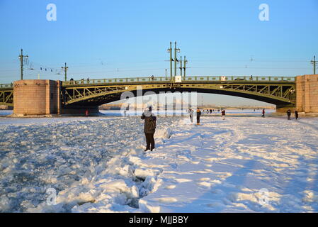 ST.PETERSBURG, RUSSIA - MARCH 07, 2018:  People take pictures of the sunset on the ice of the Neva river at the Palace bridge in Saint-Petersburg Stock Photo