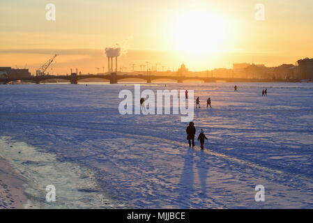 ST.PETERSBURG, RUSSIA - MARCH 07, 2018:  View of the Annunciation bridge, people on the ice of the Neva river and the sunset from Admiralty embankment Stock Photo