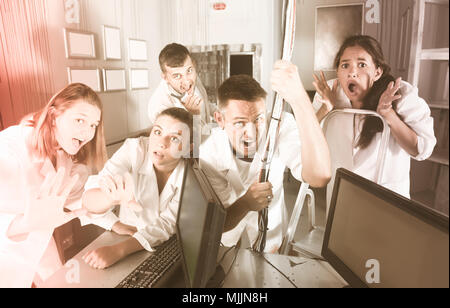 Guys and girls having fun in escape room stylized under abandoned lab Stock Photo