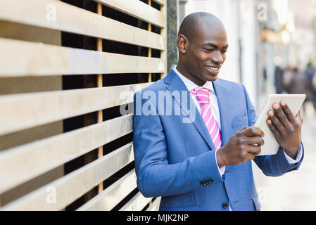 Young black businessman looking at his digital tablet outdoors. Stock Photo