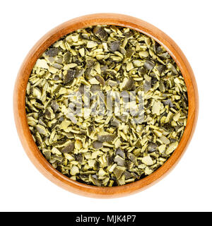Roughly chopped raw pepita pumpkin seeds in wooden bowl, used for cooking. Flat green edible summer squash seeds of Cucurbita pepo. Stock Photo