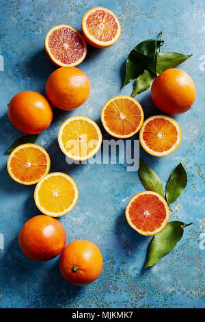 Blood oranges whole and sliced on a blue surface (seen from above). Stock Photo