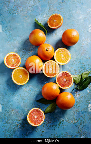 Blood oranges whole and sliced on a blue surface (seen from above). Stock Photo