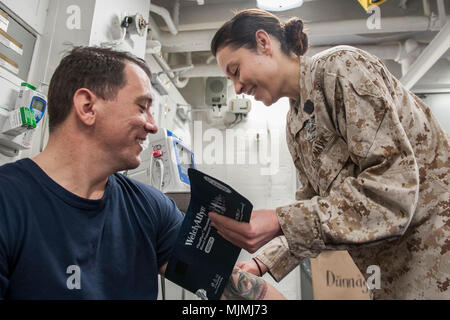 171209-N-ZS023-001 ARABIAN GULF (Dec. 9, 2017) Hospital Corpsman 1st Class Tonya Jury, a native of Golden, Colo., assigned to the health services department aboard the amphibious assault ship USS America (LHA 6), checks the blood pressure of Chief Hospital Corpsman Andy Warren, a native of Thomasville, Ga., in the main battle dressing station. America is the flagship for the America Amphibious Ready Group and, with the embarked 15th Marine Expeditionary Unit, is deployed to the U.S. 5th Fleet area of operations in support of maritime security operations to reassure allies and partners and pres Stock Photo