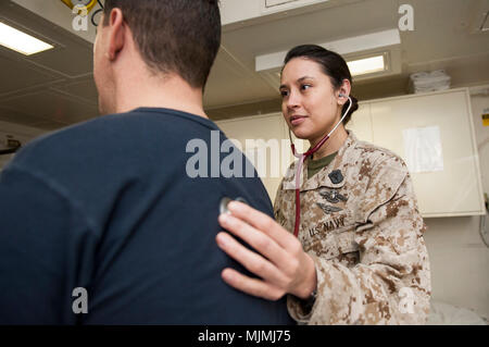 171209-N-ZS023-009 ARABIAN GULF (Dec. 9, 2017) Hospital Corpsman 1st Class Tonya Jury, a native of Golden, Colo., assigned to the health services department aboard the amphibious assault ship USS America (LHA 6), uses a stethoscope to check the vital signs of Chief Hospital Corpsman Andy Warren, a native of Thomasville, Ga., in the main battle dressing station. America is the flagship for the America Amphibious Ready Group and, with the embarked 15th Marine Expeditionary Unit, is deployed to the U.S. 5th Fleet area of operations in support of maritime security operations to reassure allies and Stock Photo