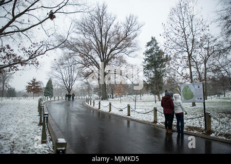 Visitors look at a map on the pathway leading to John .F Kennedy's gravesite during the first snow of the season at Arlington National Cemetery, Arlington, Virginia, Dec. 9, 2017.  (U.S. Army photo by Elizabeth Fraser / Arlington National Cemetert / released) Stock Photo